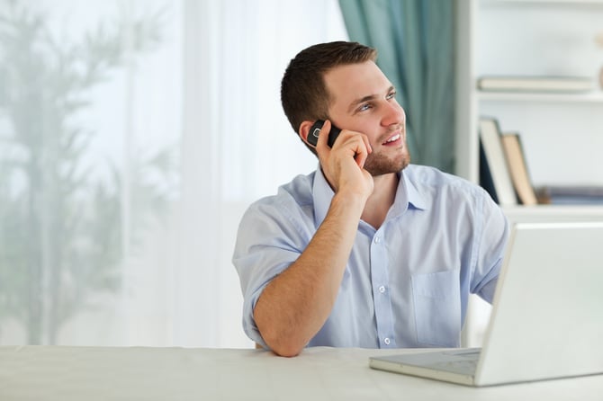 Young businessman with his cellphone in his home office